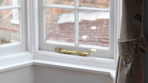A room with a bay window overlooking a brick building. - Charming 3 bedroom cottage in heart of Southwold (Southwold)