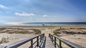 A wooden boardwalk leading to a beach with a blue umbrella and a golf cart. - Ocean-View 'Kahala Beach Bliss' Home in Galveston! (Galveston)