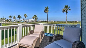 A balcony with wicker furniture and a view of the ocean and palm trees. - Ocean-View 'Kahala Beach Bliss' Home in Galveston! (Galveston)