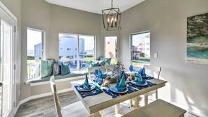 A dining area with a table set for four, large windows, and a view of the outside. - Ocean-View 'Kahala Beach Bliss' Home in Galveston! (Galveston)