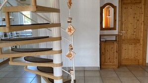 Un escalier en colimaçon avec des marches en bois et des rampes blanches, menant à l’étage supérieur.