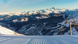 Pendenza innevata per lo sci con una seggiovia e vista sulle montagne.