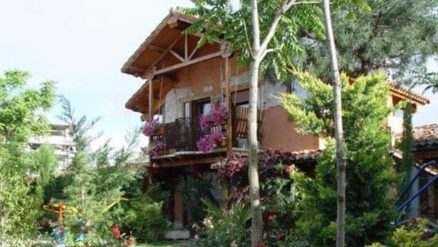 A two-story wooden house with a balcony, surrounded by lush greenery and trees. - Classic Double Room: Double studio, with capacity for two people. (Olmedo)
