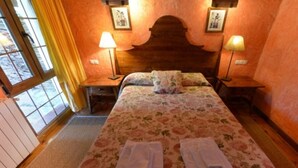 A room with a bed, two bedside lamps, a wooden headboard, and a window with curtains. - Classic Double Room: Double studio, with capacity for two people. (Olmedo)