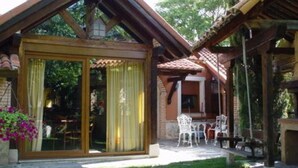 A building with a large sliding glass door, a patio area with outdoor furniture, and a tiled roof. - Basic Triple Room: Private entrance and porch (Olmedo)