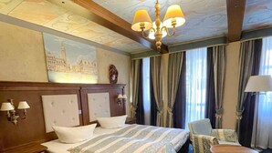 Una habitación de hotel con una cama grande, una silla, una mesita y un candelabro.