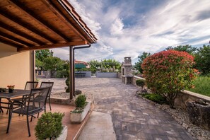 Uma área de pátio externa com pérgola, assentos e vista para a paisagem ao redor.