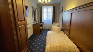 Een hotelkamer met een bed, een bureau, een stoel, een kledingkast en een grote spiegel.