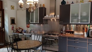 A modern kitchen with a gas stove, stainless steel cabinets, and a dining area with a round table and chairs.