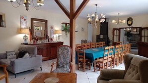 A spacious living room with a dining area, wooden furniture, and a chandelier.