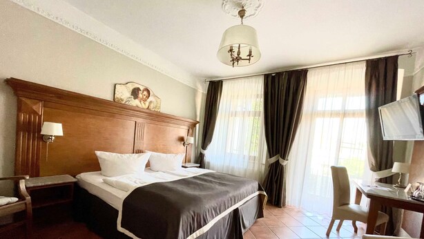 Een hotelkamer met een groot bed, een bureau met een computer, een stoel en een televisie.