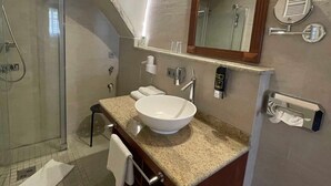 Een moderne badkamer met een ruime wastafel, een douchecabine van glas en een spiegel met ingebouwde verlichting.