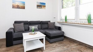 Una sala moderna con un sofá seccional gris, una mesa de centro blanca y dos cuadros en la pared.