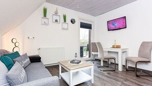 Ein modernes Wohnzimmer mit grauem Sofa, weißem Couchtisch und einem an der Wand befestigten Fernseher.