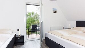 Ein Schlafzimmer mit zwei Betten, einer Schiebetür zu einem Balkon und einem kleinen Bild an der Wand.