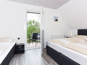 A bedroom with two beds, a sliding door to a balcony, and a small picture on the wall.