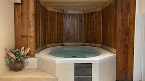 Un bain à remous installé dans un coin, avec des murs en bois et un sol carrelé.