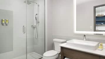 A modern bathroom with a glass shower enclosure, a white toilet, and a vanity with a mirror above the sink.