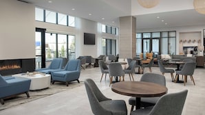 A spacious lounge area with modern seating, a fireplace, and large windows offering views. - Element by Marriott Seattle Sea-Tac Airport (Tukwila)