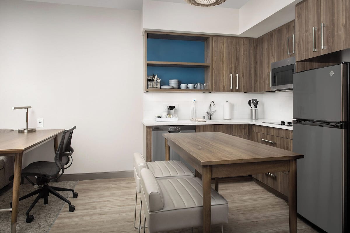 A modern kitchen with wooden cabinets, a stainless steel refrigerator, and a built-in microwave.