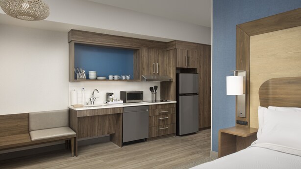 A modern hotel room with a kitchenette, a bed, a bench, and a nightstand. - Element by Marriott Seattle Sea-Tac Airport (Tukwila)