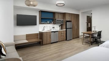 Una cocina moderna con armarios de madera, microondas y refrigerador. Hay una mesa de comedor con sillas y una banca.