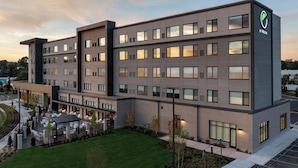 A modern hotel building with multiple floors, a covered outdoor seating area, and a parking lot. - Element by Marriott Seattle Sea-Tac Airport (Tukwila)