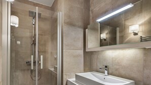 A modern bathroom with a glass-enclosed shower, a white sink, and a large mirror. - Charming apartment in Courchevel Village, near slopes, WIFI, parking included (Courchevel 1550)