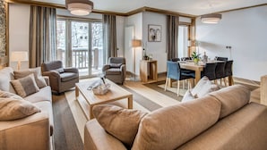 Una sala de estar moderna con un sofá, sillones, una mesa de comedor con sillas y un balcón con vistas.
