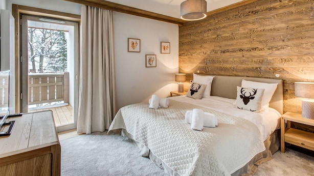 Un dormitorio acogedor con una cama grande, cabecera de madera y vistas a una terraza nevada.