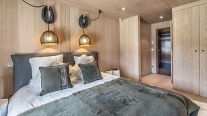 Ein modernes Schlafzimmer mit einem großen Bett, zwei Pendelleuchten, einem Kleiderschrank und einem Aufzug.
