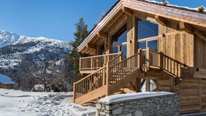 Eine Holzhütte mit Steinunterbau, einer Holztreppe und großen Fenstern.