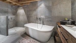 Ein modernes Badezimmer mit einer freistehenden Badewanne, einem hölzernen Waschtisch und einer Duschkabine.