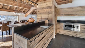Eine moderne Küche mit Holzausstattung und einer großen Kochinsel, inklusive eingebautem Ofen und einer eleganten Arbeitsplatte.