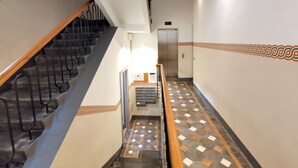 Ein Flur mit Treppe, einer Tür und einem gemusterten Boden.