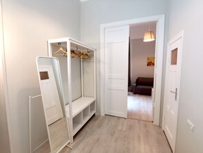 Una habitación con un armario blanco, un espejo y una percha con ropa.