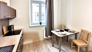 Eine kleine Küche mit Fenster, einem Esstisch mit Stühlen und einem kleinen Topfpflanzen.
