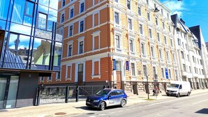 Ein mehrstöckiges Gebäude mit einer Mischung aus moderner und klassischer Architektur, das große Fenster und einen markanten Eingang aufweist.