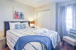 A neatly made bed with a striped bedspread, a bedside lamp, and a wall-mounted artwork.