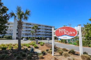 A sign for Turn of River hotel with a view of a multi-story building in the background.