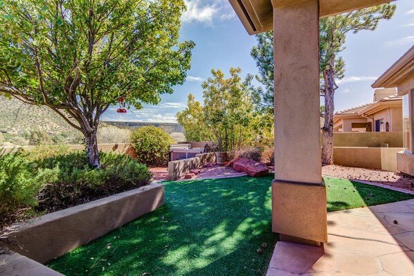 Un patio cuidado con césped artificial, una pérgola y vistas a un paisaje montañoso.