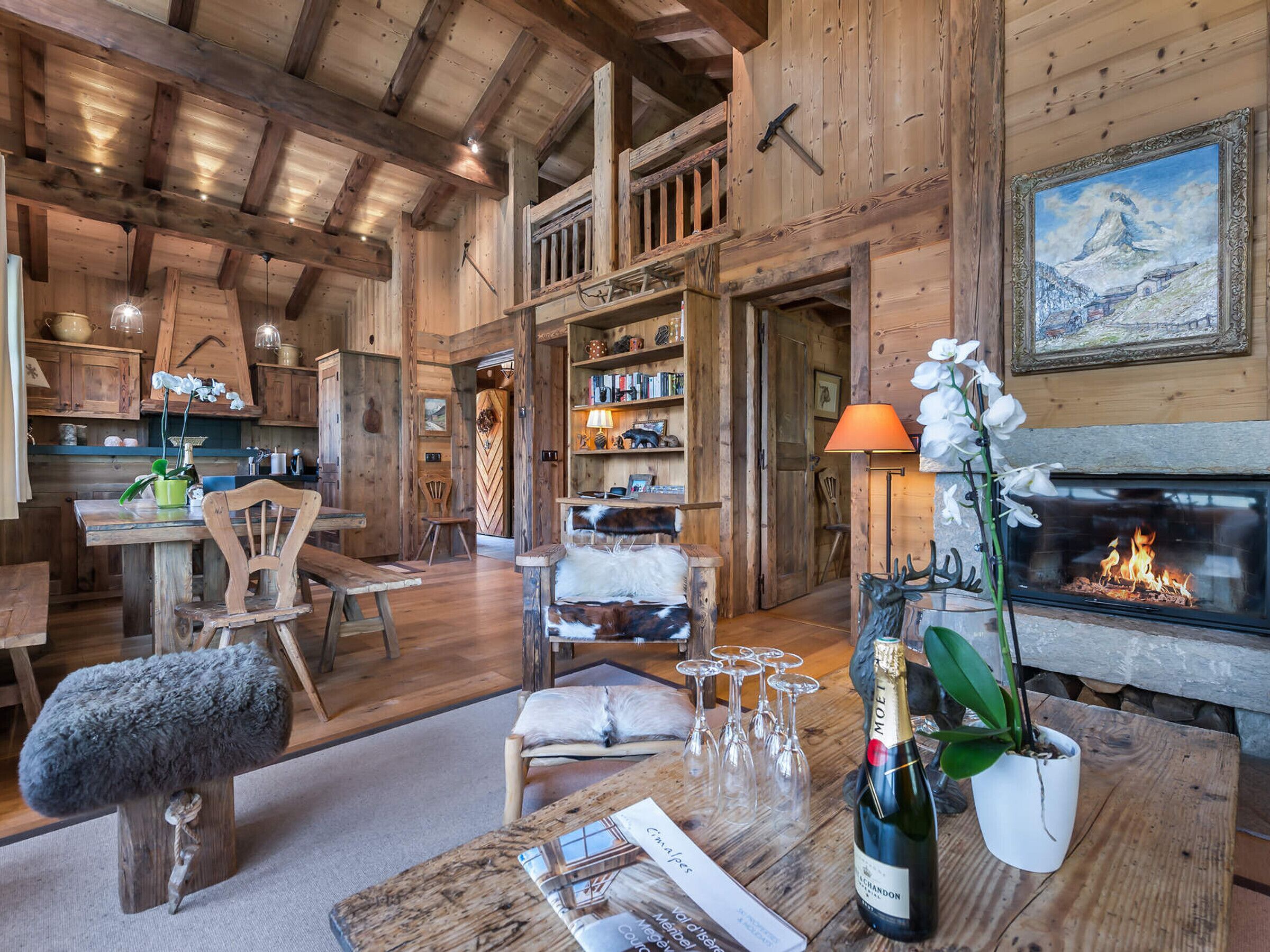 A rustic wooden interior with a fireplace, wooden shelves, and a dining area.