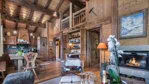 Un intérieur rustique avec des éléments en bois, notamment une cheminée, des étagères en bois et un coin repas.