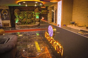A lobby with a marble floor, a reception desk, a plush seating area, and a decorative wall with a waterfall feature.