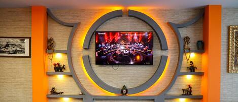 Una sala de estar moderna con un televisor de pantalla plana grande montado en un diseño circular en la pared, una chimenea y un área de estar confortable con sofás y una mesa de centro.