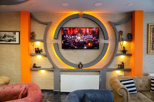 Una sala de estar moderna con un televisor de pantalla plana grande montado en un diseño circular en la pared, una chimenea y un área de estar confortable con sofás y una mesa de centro.