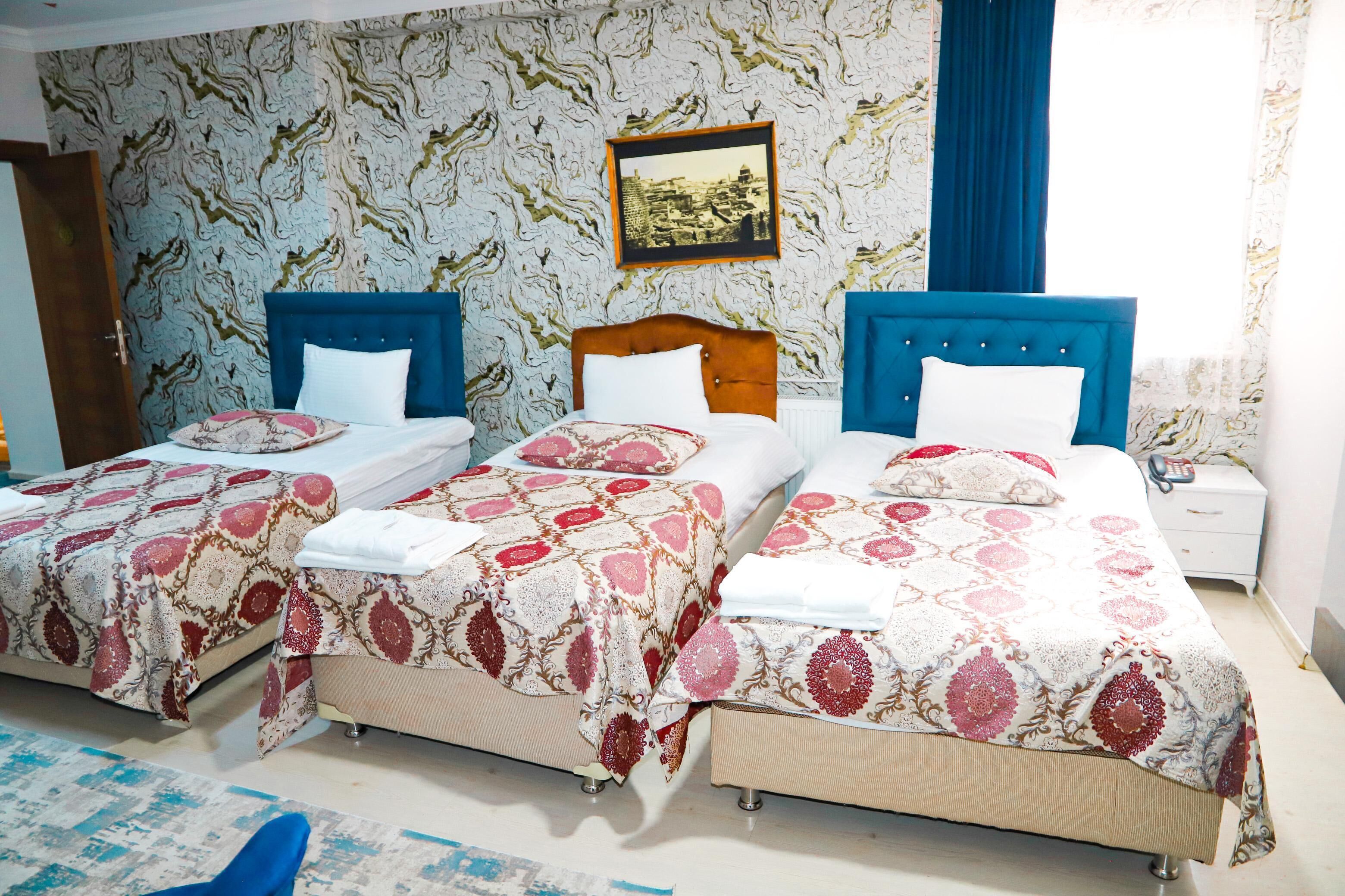 A hotel room with two single beds, a wooden headboard, a nightstand, and a patterned wallpaper.