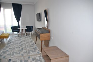 A hotel room with a bed, a desk, a chair, a small table, and a mirror.