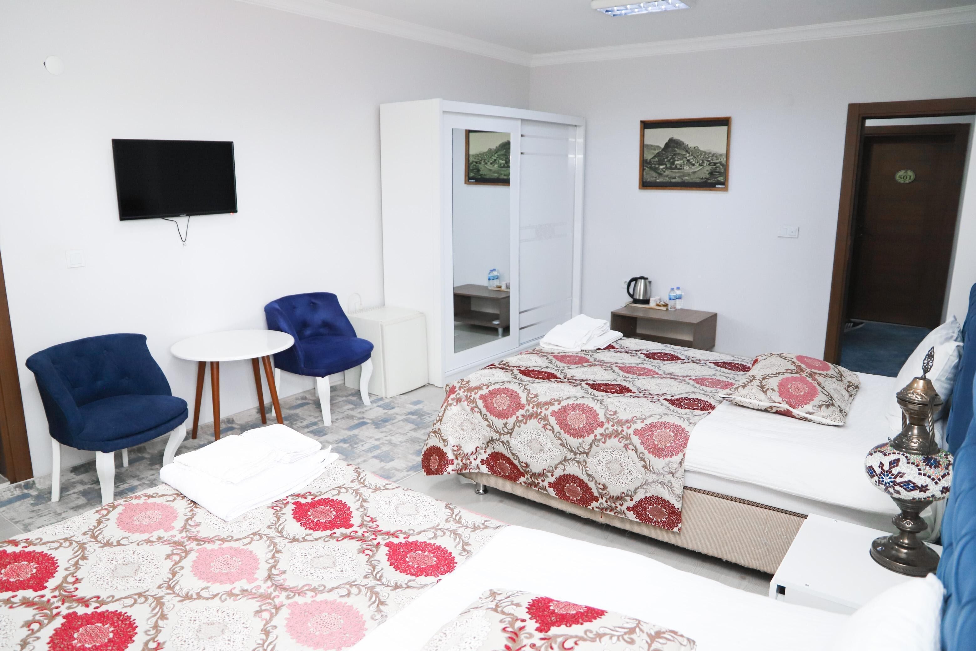 Una habitación de hotel con cama, televisión, armario, escritorio y una silla.