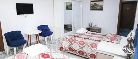 Una habitación de hotel con cama, televisión, armario, escritorio y una silla.